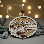 Wooden oval ornament engraved with a Twelve Days of Christmas scene, hanging against warm out-of-focus lights