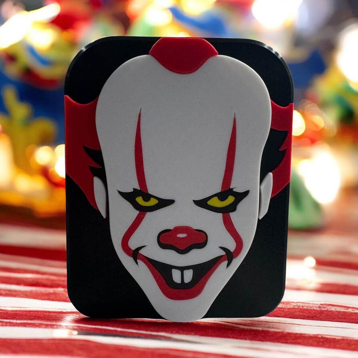 Close view of the creepy clown soap dispenser cover on a red and white striped background