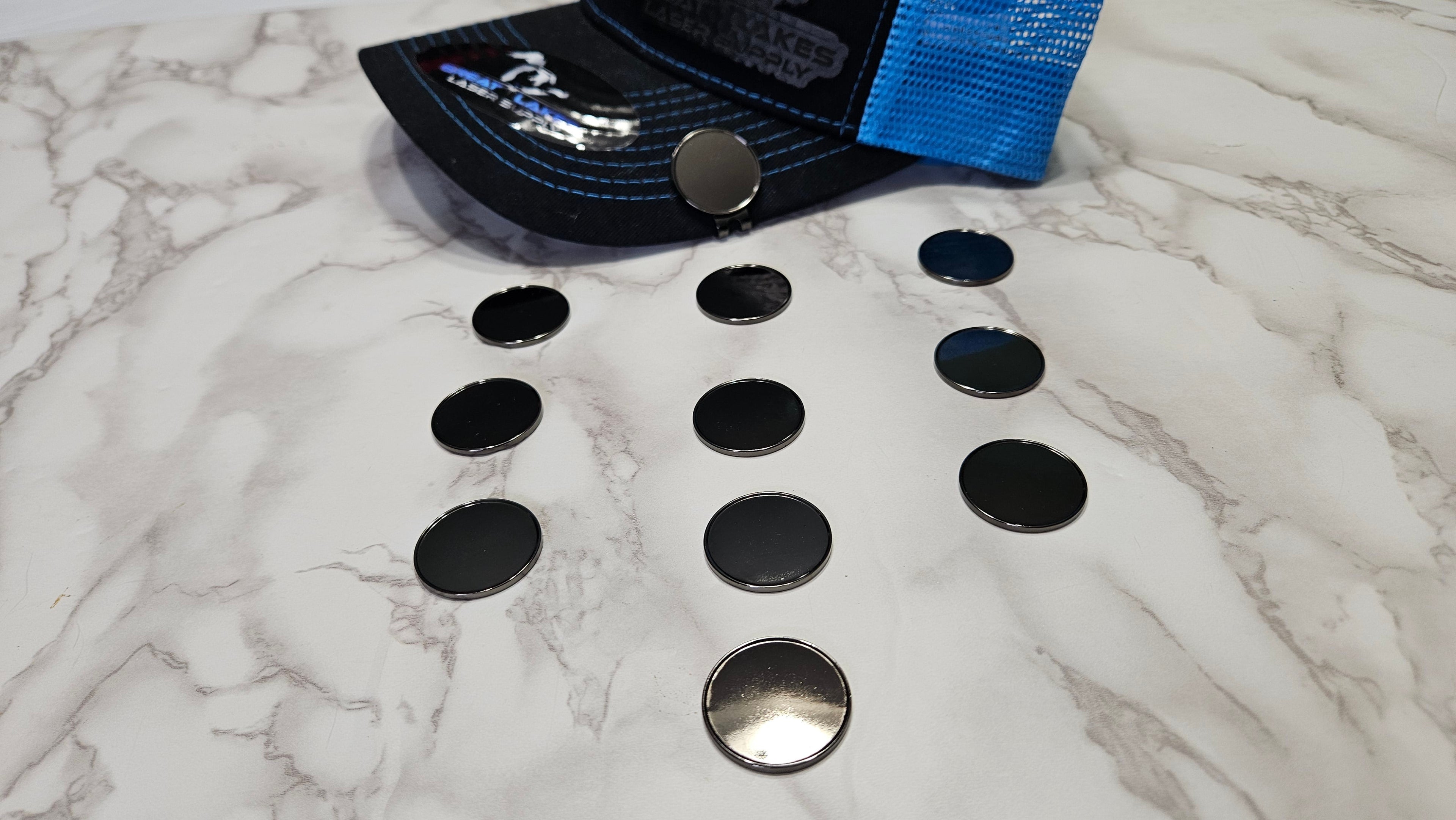 A scattered group of round black golf ball markers on a marble surface