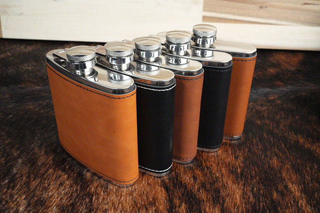 Leatherette hip flasks lined up to show the tan and black color options and stainless steel caps