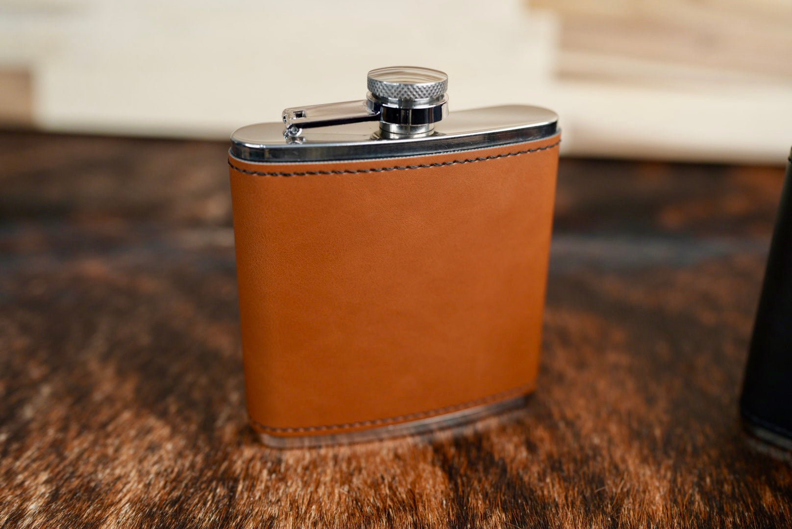 Heritage Rawhide leatherette hip flask in warm tan with a stainless steel cap and hinged retainer