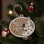 Wooden oval ornament engraved with a Deck the Halls scene of a girl trimming a Christmas tree, hanging on a pine bough with red baubles