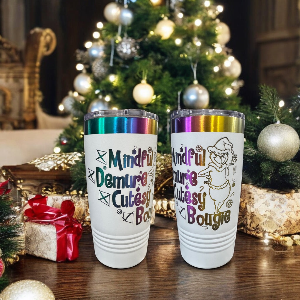 Two white Prism tumblers engraved Mindful, Demure, Bougie in rainbow lettering by a Christmas tree