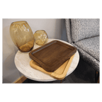 Alder and walnut trays stacked on a side table beside glass vases