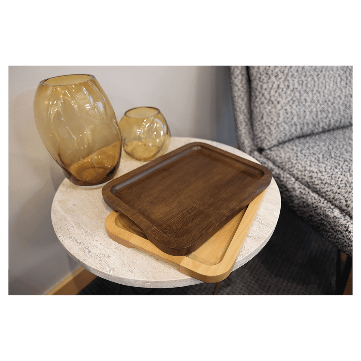 Alder and walnut trays stacked on a side table beside glass vases