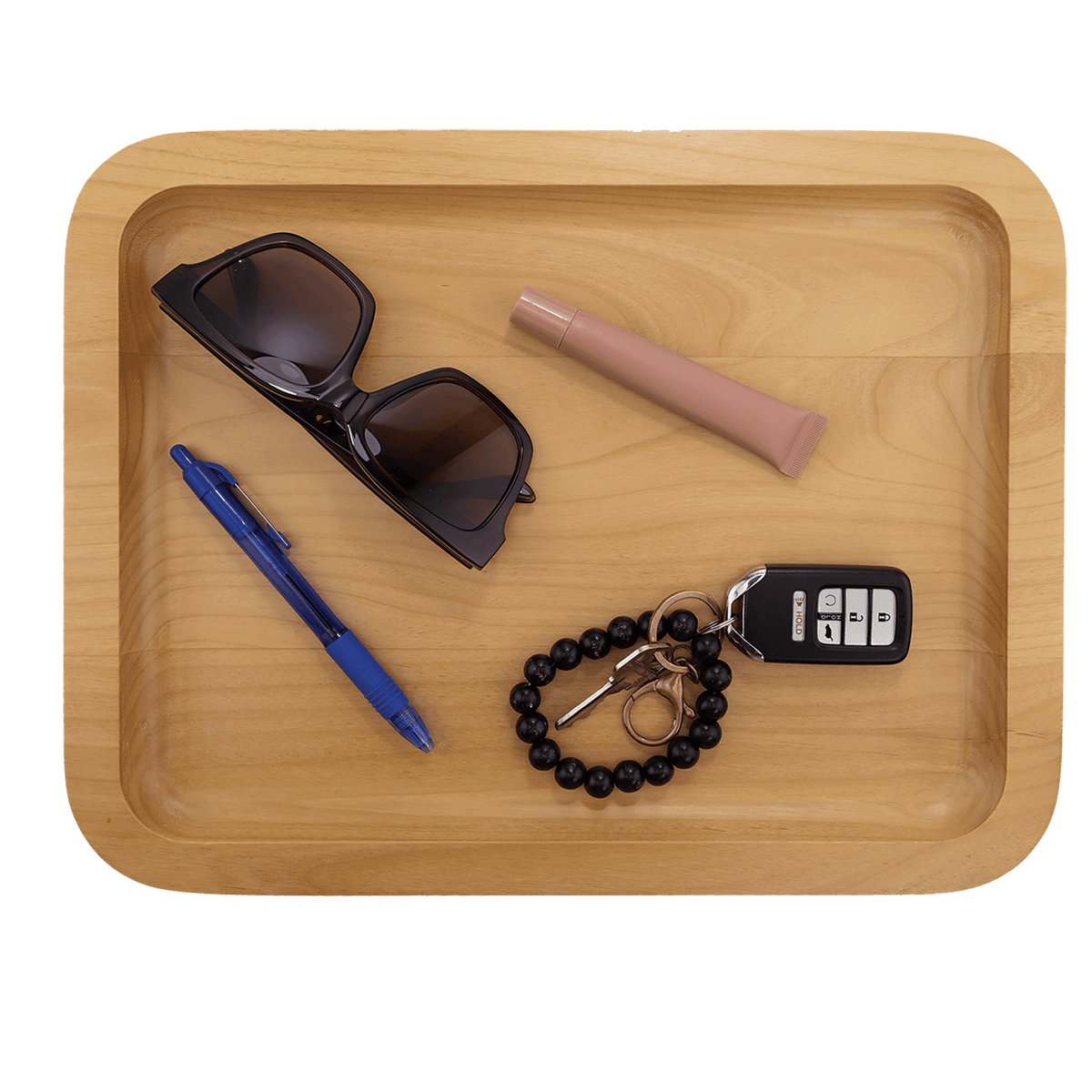 Alder tray holding sunglasses, a pen, keys and a bracelet