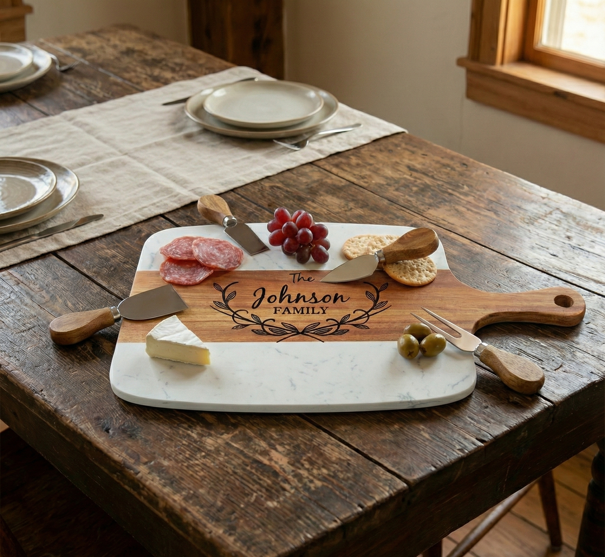 Marble and acacia serving board on a kitchen island, styled with cheese, crackers and fruit