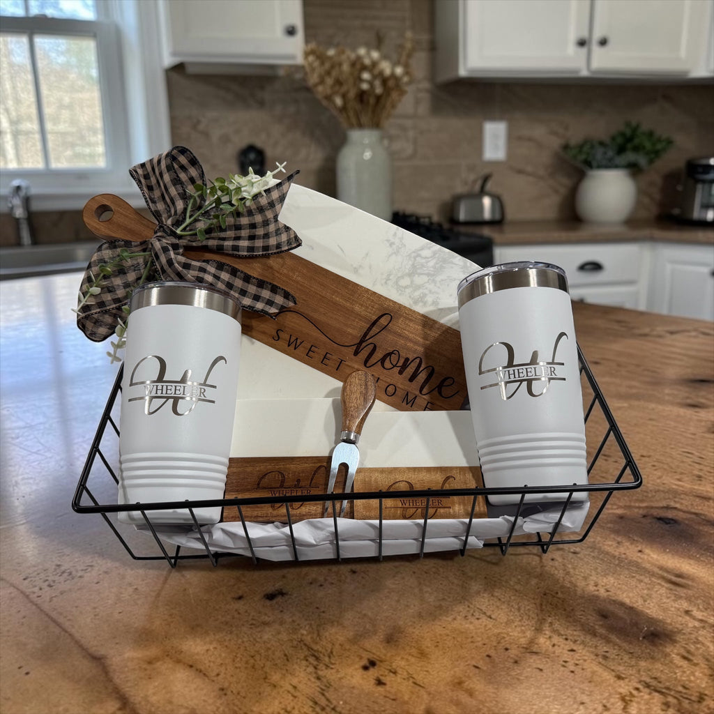 Real estate closing gift package arranged in a black wire basket with serving board, coasters and two tumblers