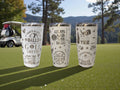 Three engraved tumblers with a golf design standing on a golf course fairway