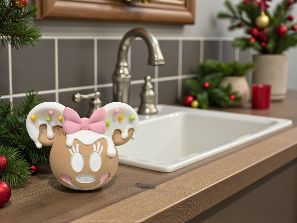 Gingerbread-styled soap dispenser cover with mouse ears and a pink bow, standing beside a kitchen sink