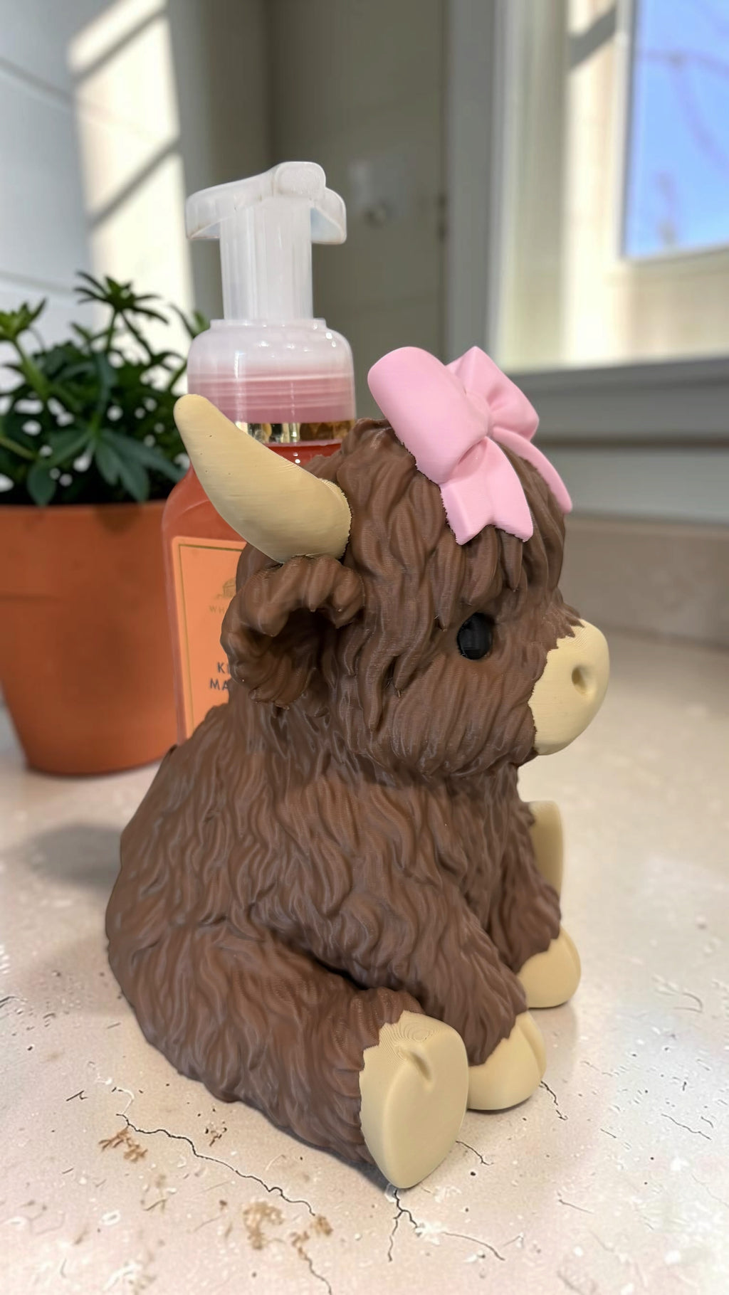 Opposite side of the Highland cow soap holder showing the foaming soap bottle held behind its fluffy back