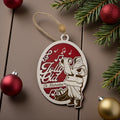 Wooden oval ornament engraved with a Jolly Old St. Nicholas scene, hanging against a pine bough with red baubles