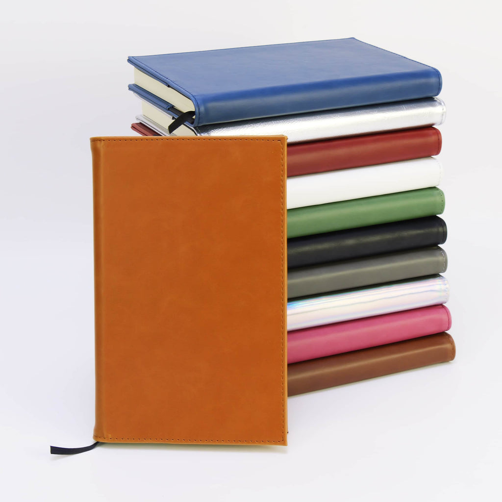 Leatherette journals stacked by color with a tan journal standing in front