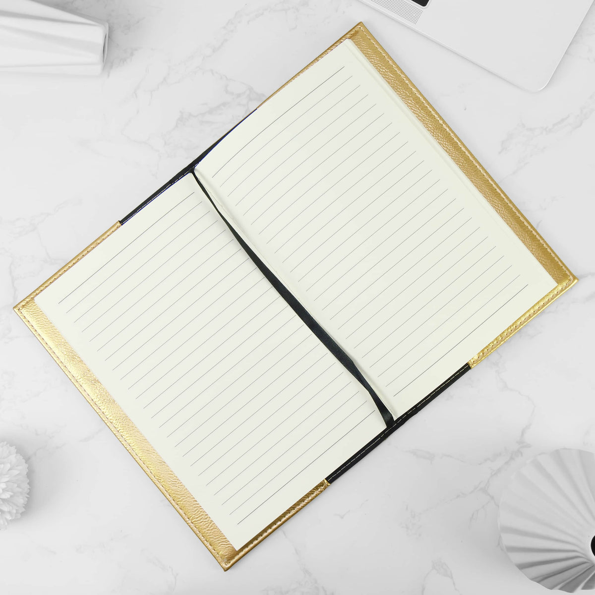 Refill notebook seated in a metallic gold leatherette journal cover, opened flat with the ribbon bookmark laid across the lined pages