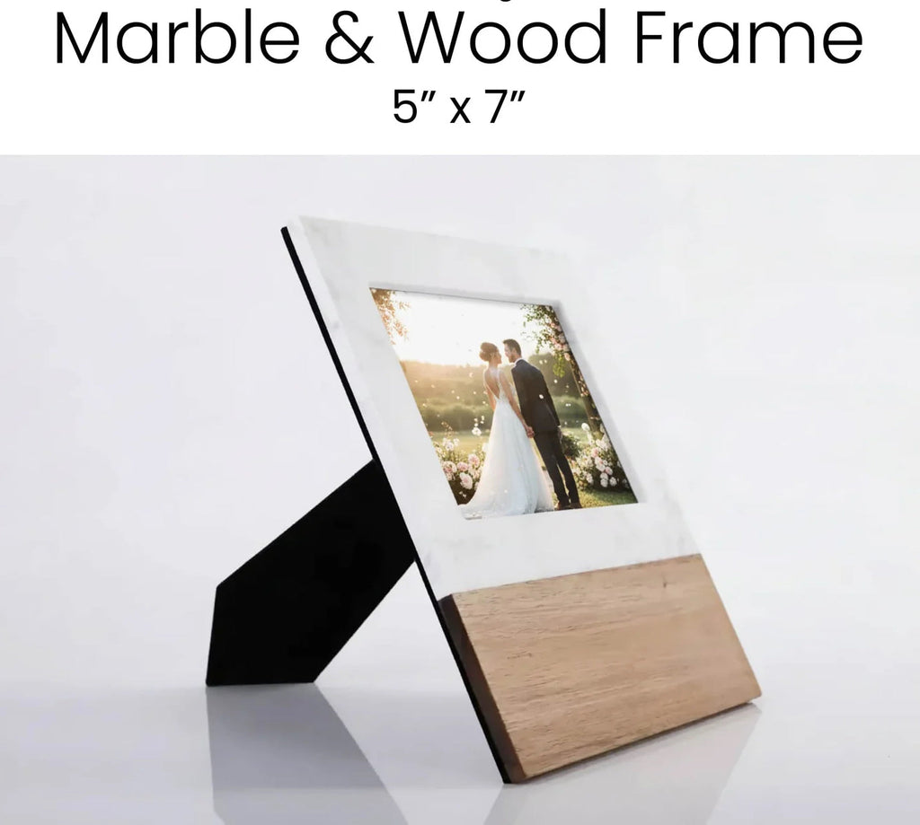 Marble and acacia wood 5x7 picture frame standing at an angle with a wedding photo in it, black fold-out stand visible behind
