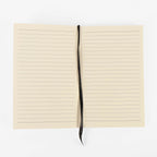 Refill notebook opened flat showing the cream lined pages and black ribbon bookmark