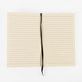 Lined journal refill notebook open flat, showing ruled cream pages and the ribbon bookmark
