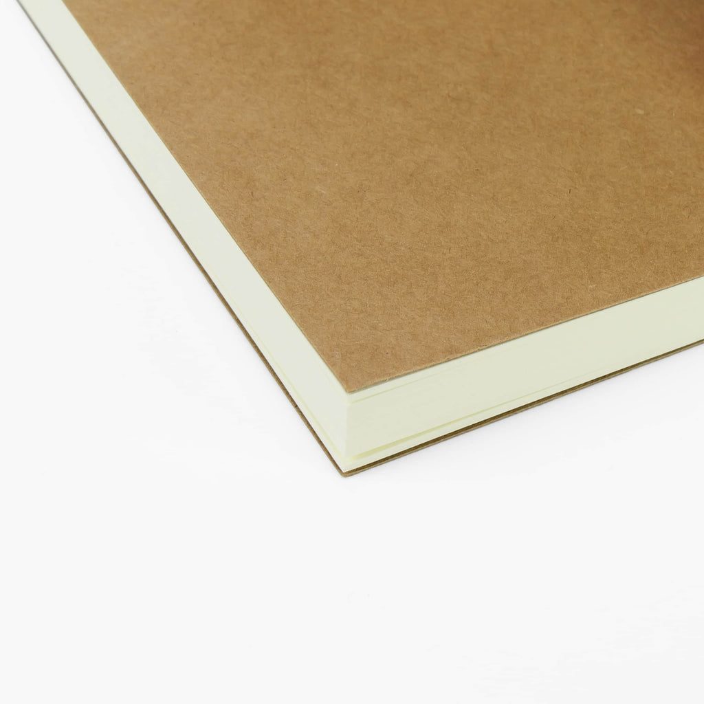 Close view of the kraft cover and cream page edges of a refill notebook