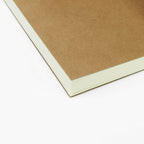 Close view of the kraft cover and cream page edges of a refill notebook
