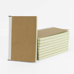 Kraft-cover refill notebooks stacked, showing the cream page block from the side