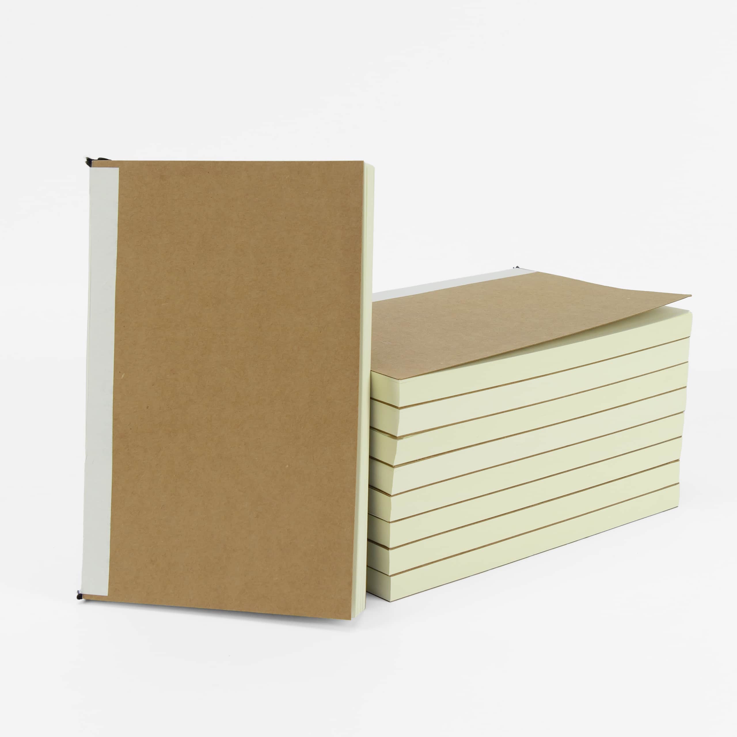 Kraft-cover refill notebooks stacked, showing the cream page block from the side