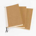 Two closed journal refill notebooks stacked, showing the kraft cover and cream page edges