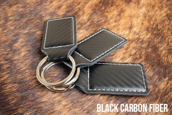 Three black carbon fiber Premium Leatherette keychains with a woven texture, fanned out on a split ring.