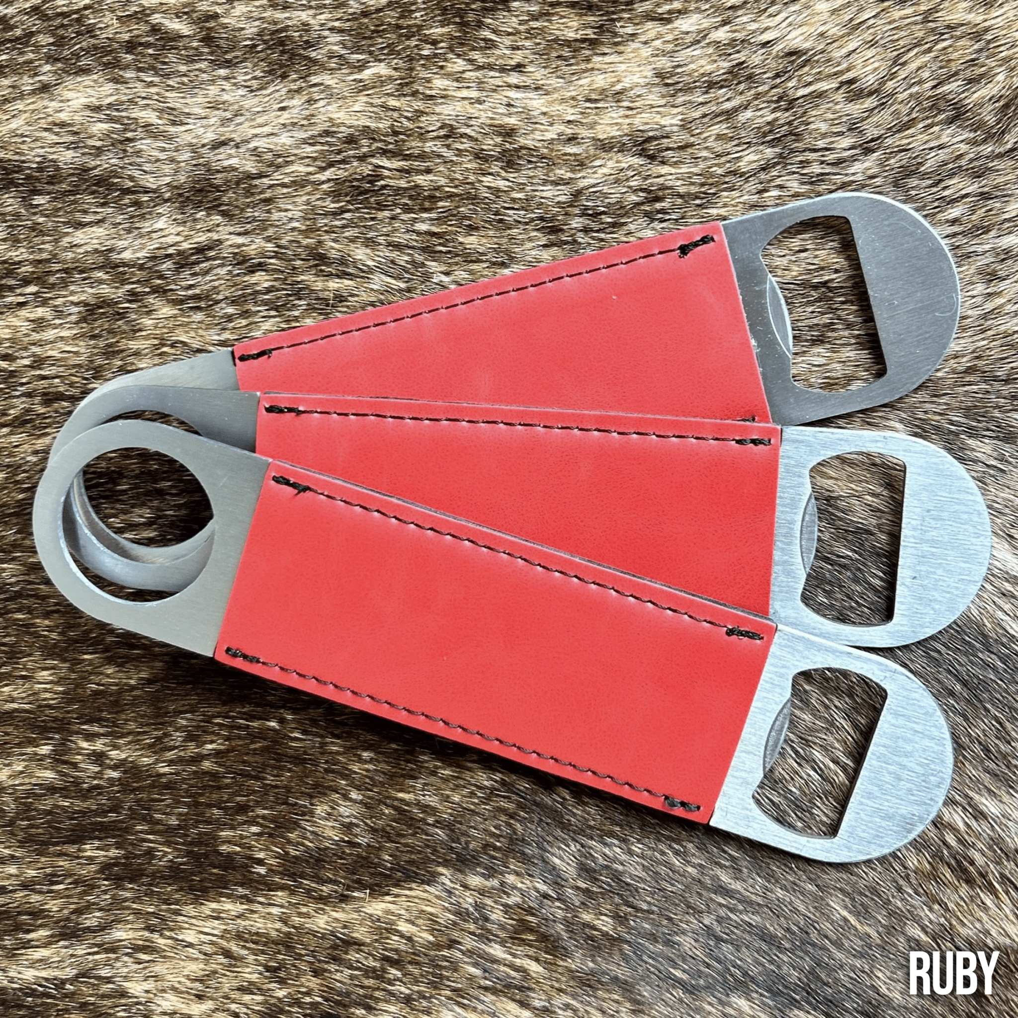 Three stainless steel bar bottle openers wrapped in Ruby red Premium Leatherette, fanned out to show the wrap and the opener end.