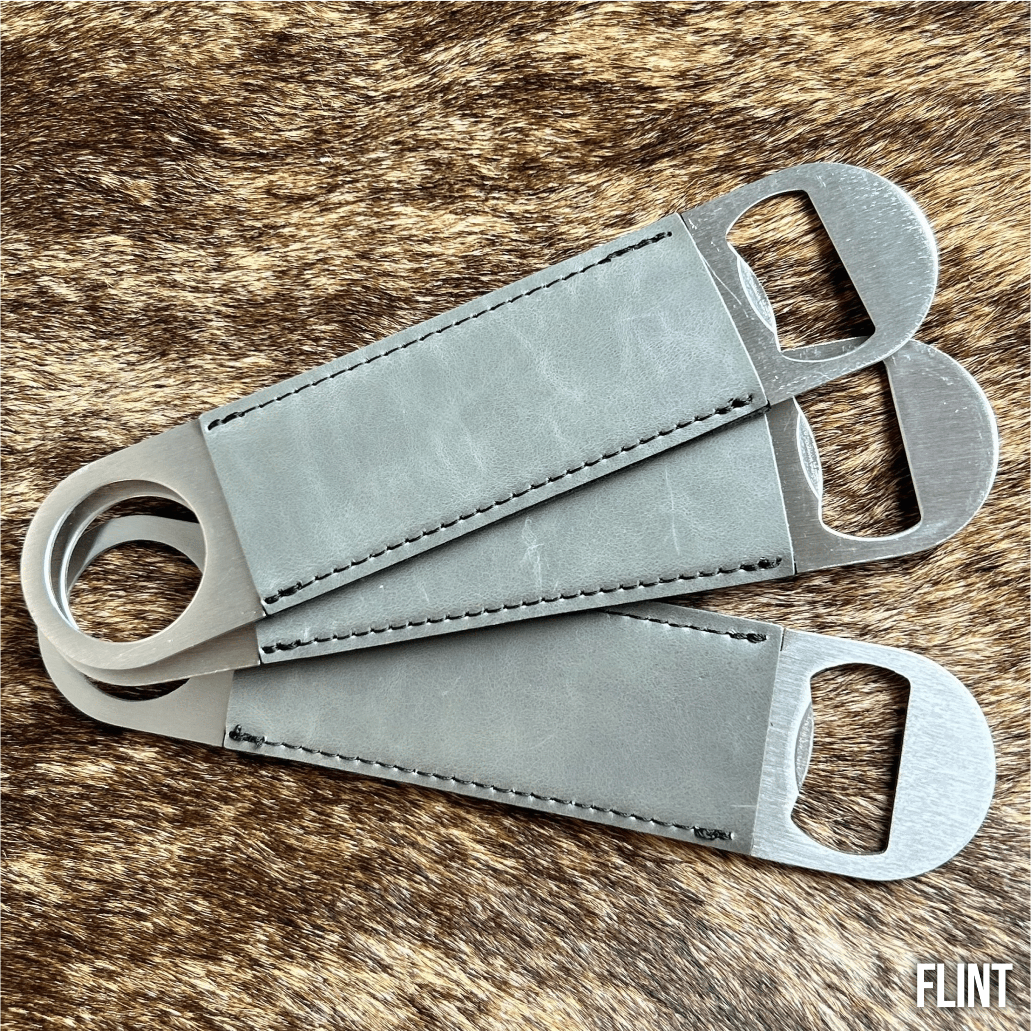 Three stainless steel bar bottle openers wrapped in Flint grey Premium Leatherette, fanned out to show the wrap and the opener end.