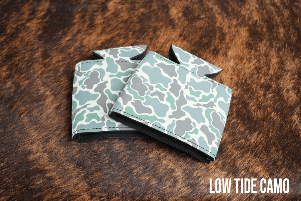 Low Tide Camo Premium Leatherette can coolers in a muted camouflage pattern, laid flat and collapsed.