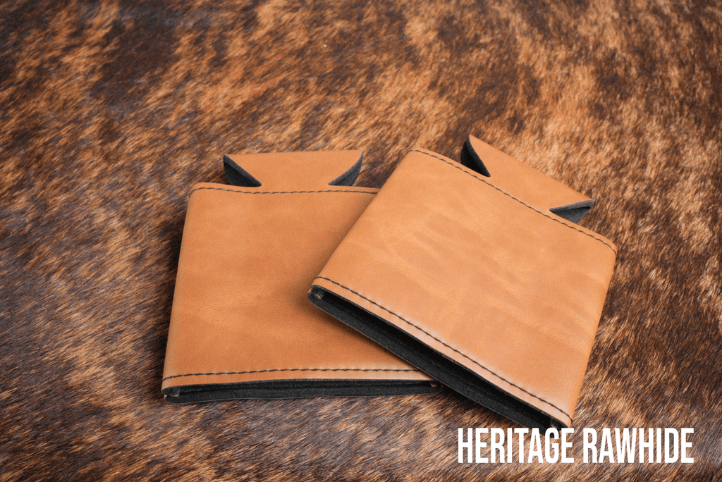 Two Rawhide tan Premium Leatherette can coolers laid flat on a cowhide surface, shown collapsed.