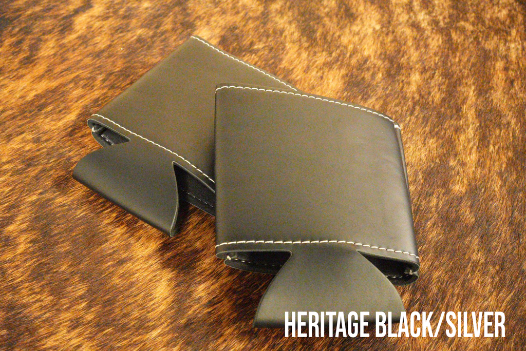 Black Premium Leatherette can coolers that engrave to silver, shown folded on a cowhide surface.