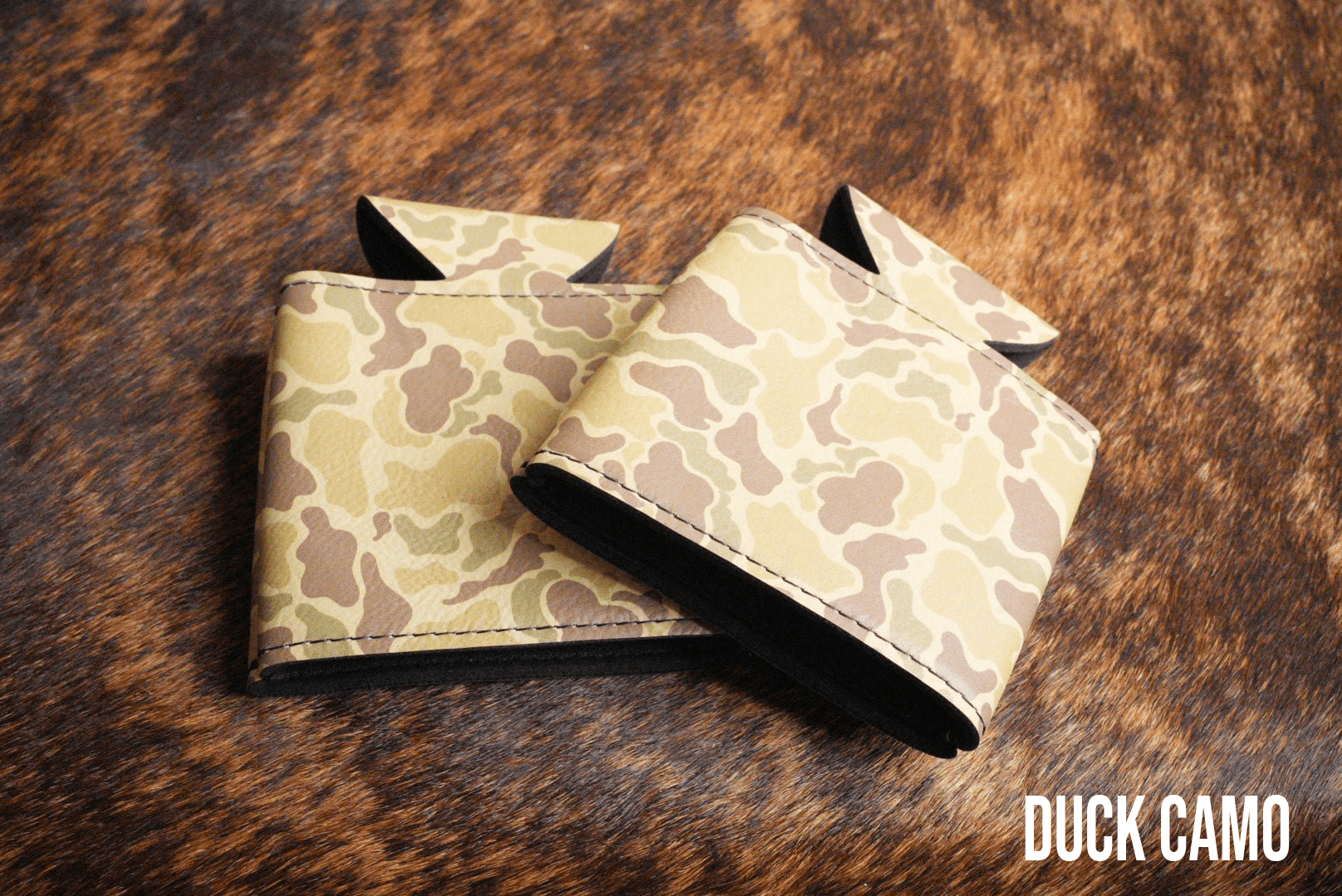 Duck Camo Premium Leatherette can coolers in a waterfowl camouflage pattern, laid flat and collapsed.
