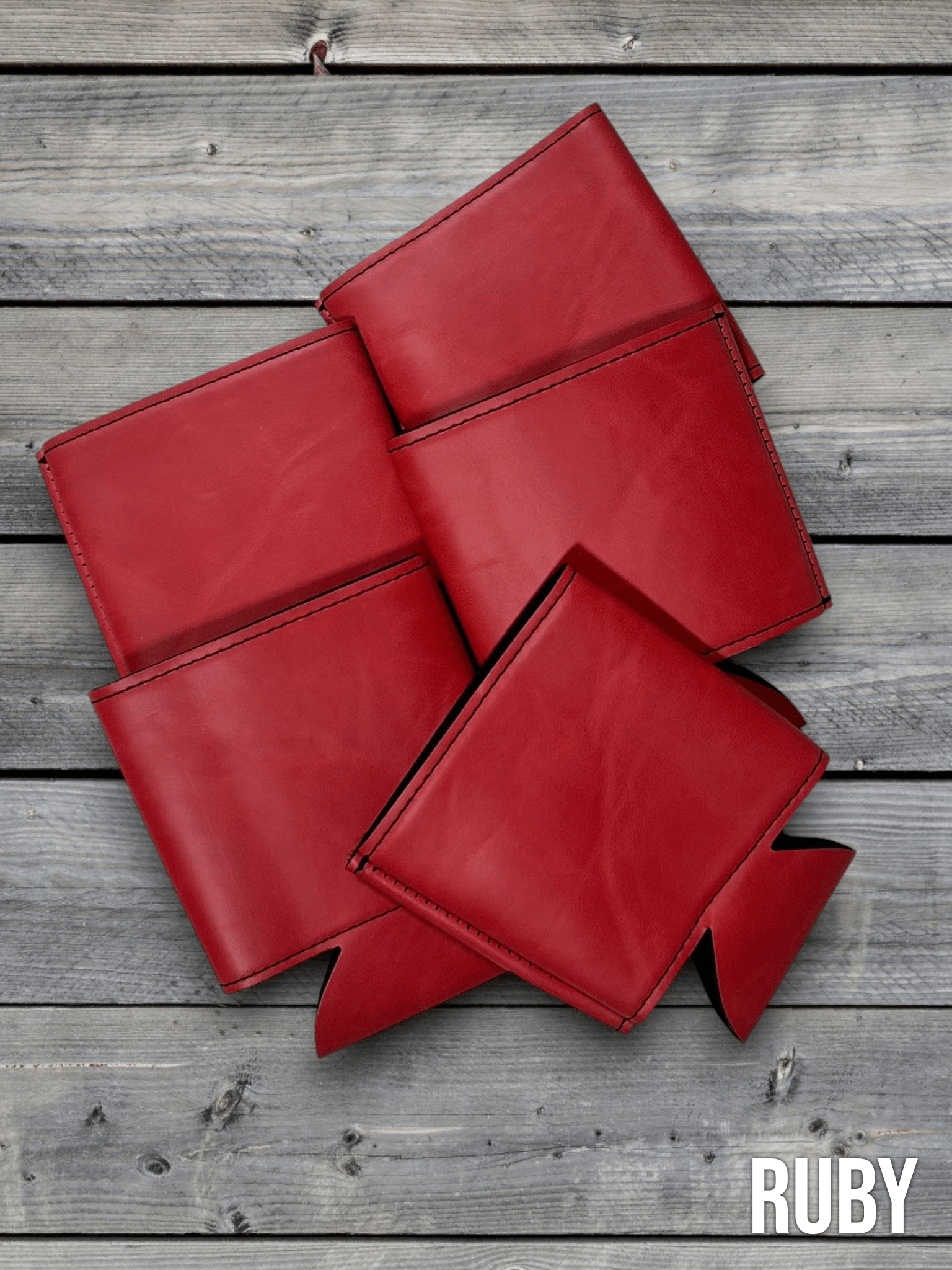 Several Ruby red Premium Leatherette can coolers laid flat on weathered wood, shown collapsed.