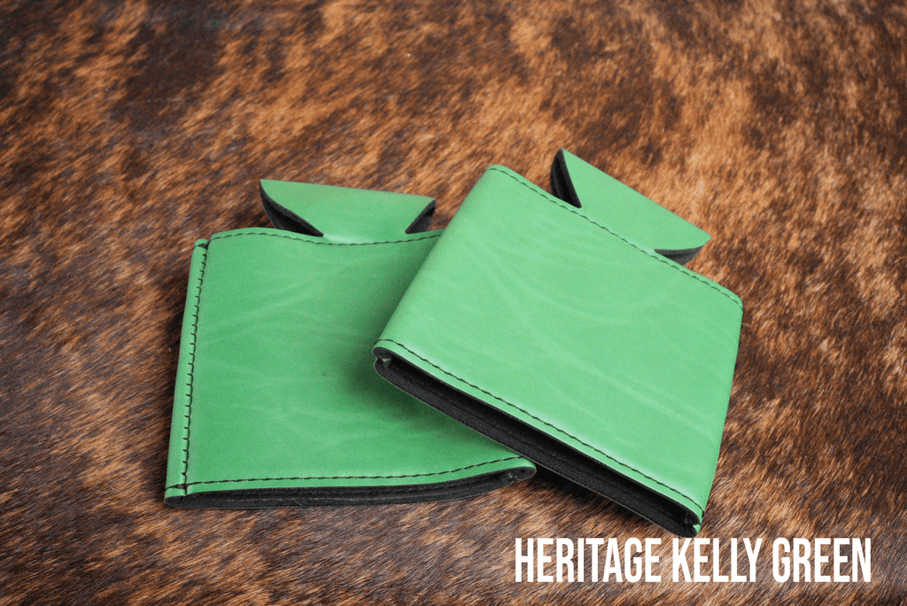 Several Kelly Green Premium Leatherette can coolers laid flat on weathered wood, shown collapsed.