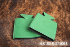 Several Kelly Green Premium Leatherette can coolers laid flat on weathered wood, shown collapsed.
