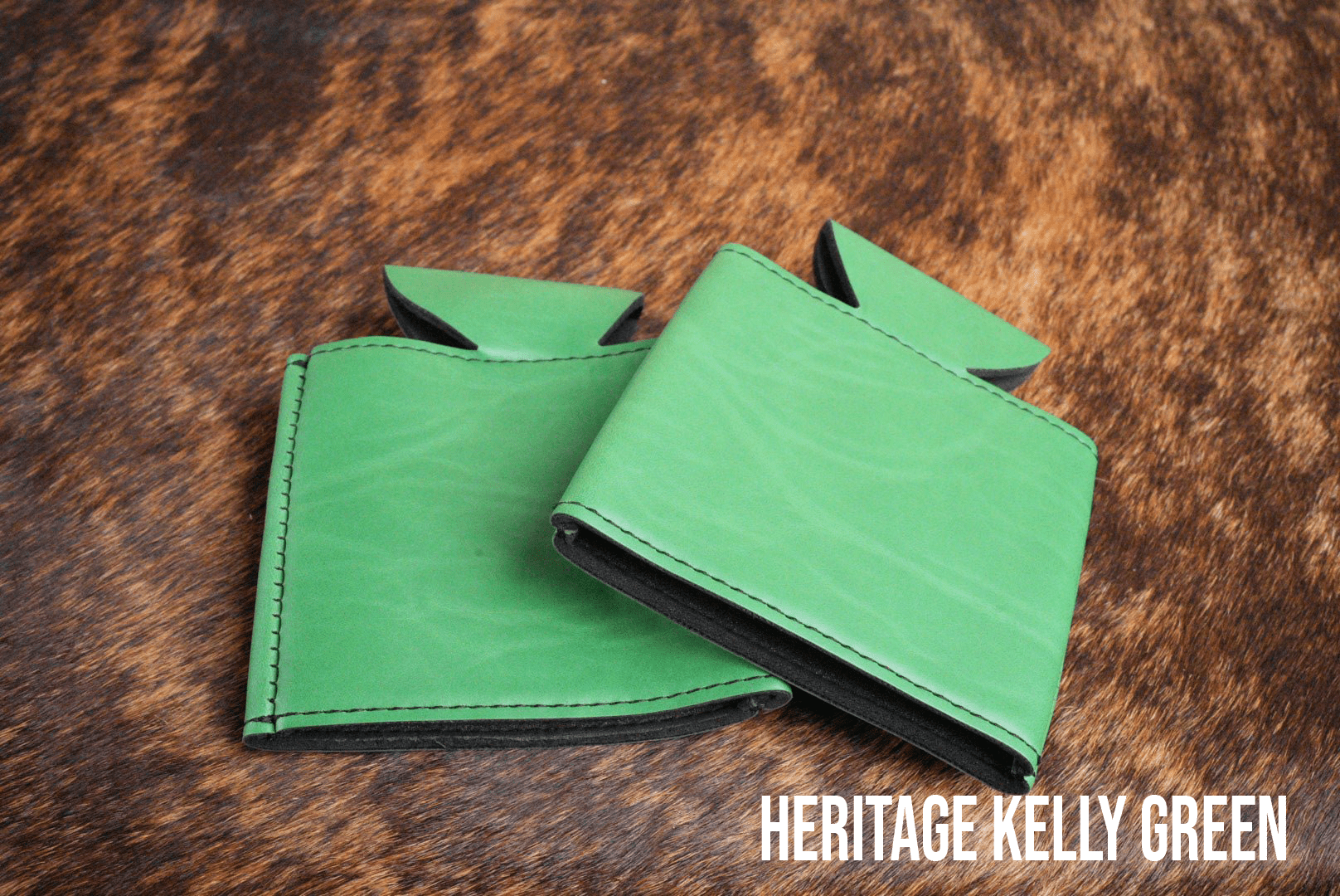 Several Kelly Green Premium Leatherette can coolers laid flat on weathered wood, shown collapsed.