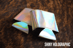 Shiny holographic Premium Leatherette can coolers with a bright iridescent finish, laid flat and collapsed.