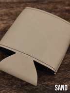 Several Sand beige Premium Leatherette can coolers laid flat on weathered wood, shown collapsed.