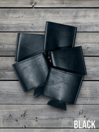 Several Black Premium Leatherette can coolers laid flat on weathered wood, shown collapsed.