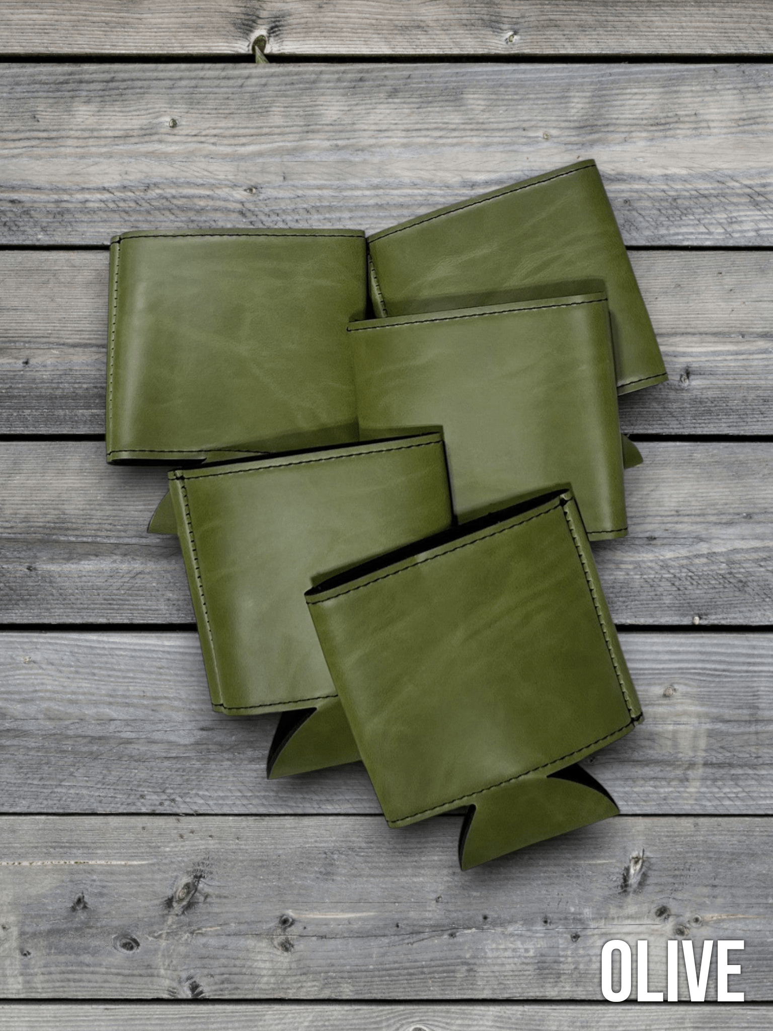Several Olive green Premium Leatherette can coolers laid flat on weathered wood, shown collapsed.