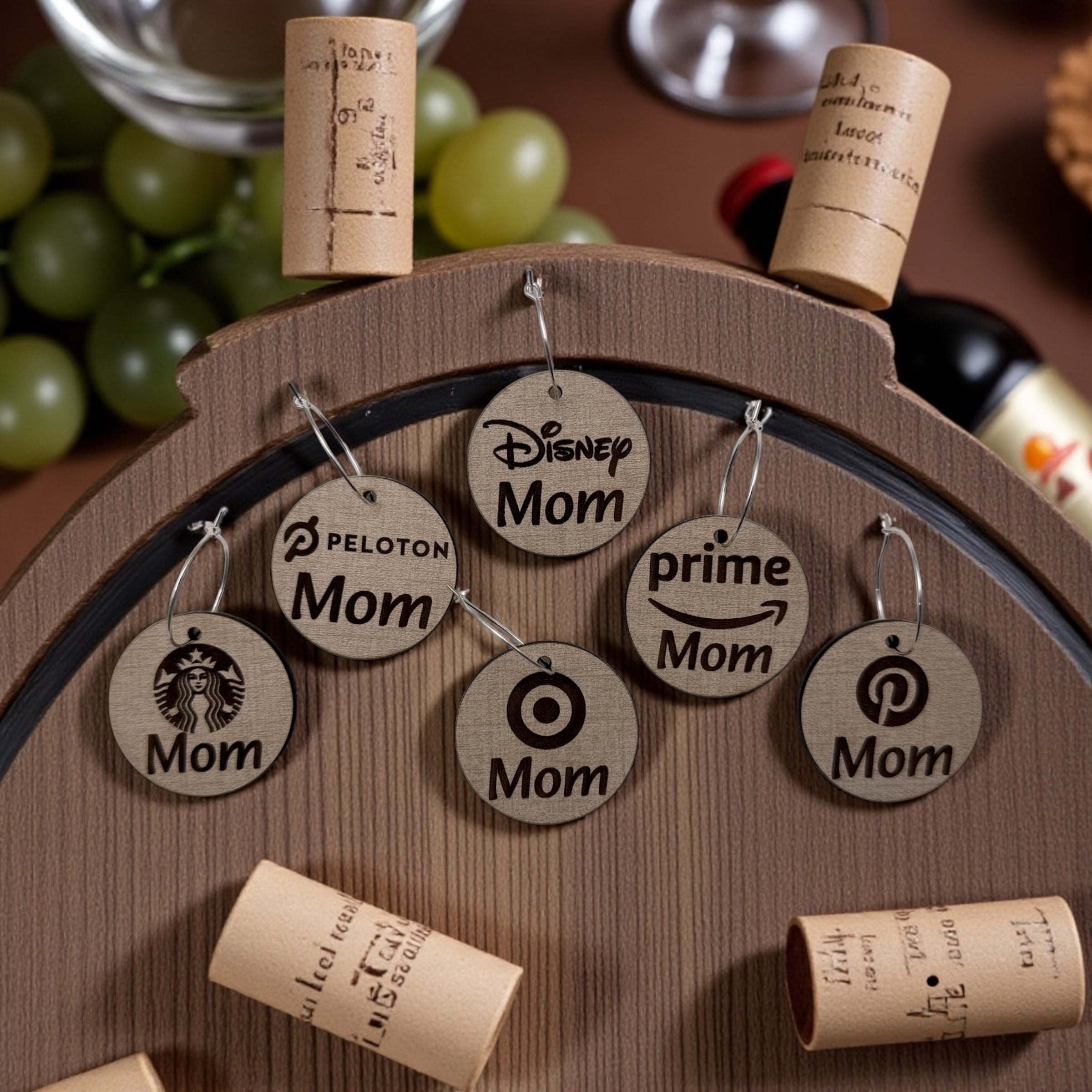 Round wooden Mom Life wine charms and corks arranged on the top of a wine barrel