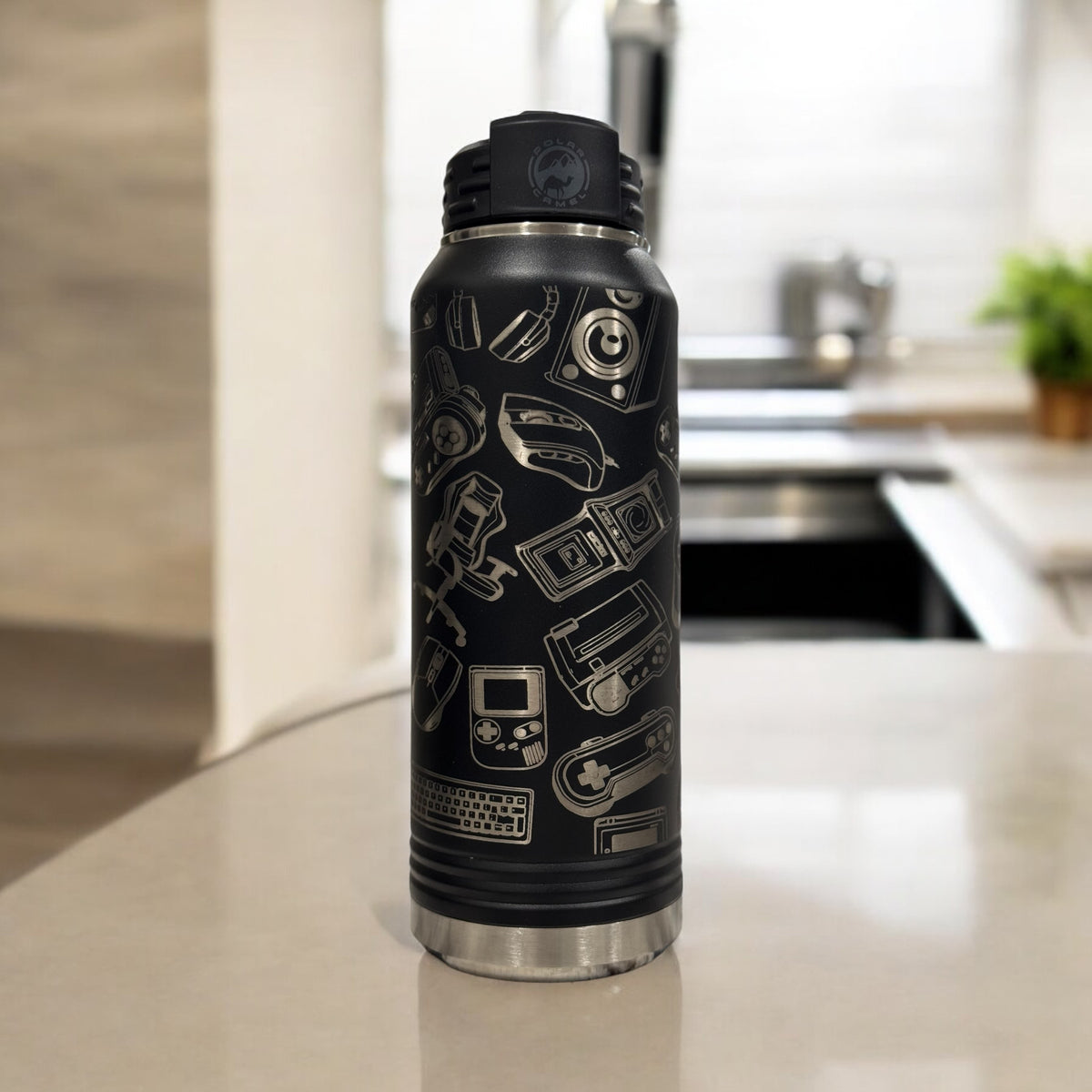 Black insulated water bottle engraved with a collage of video game icons, standing on a kitchen counter
