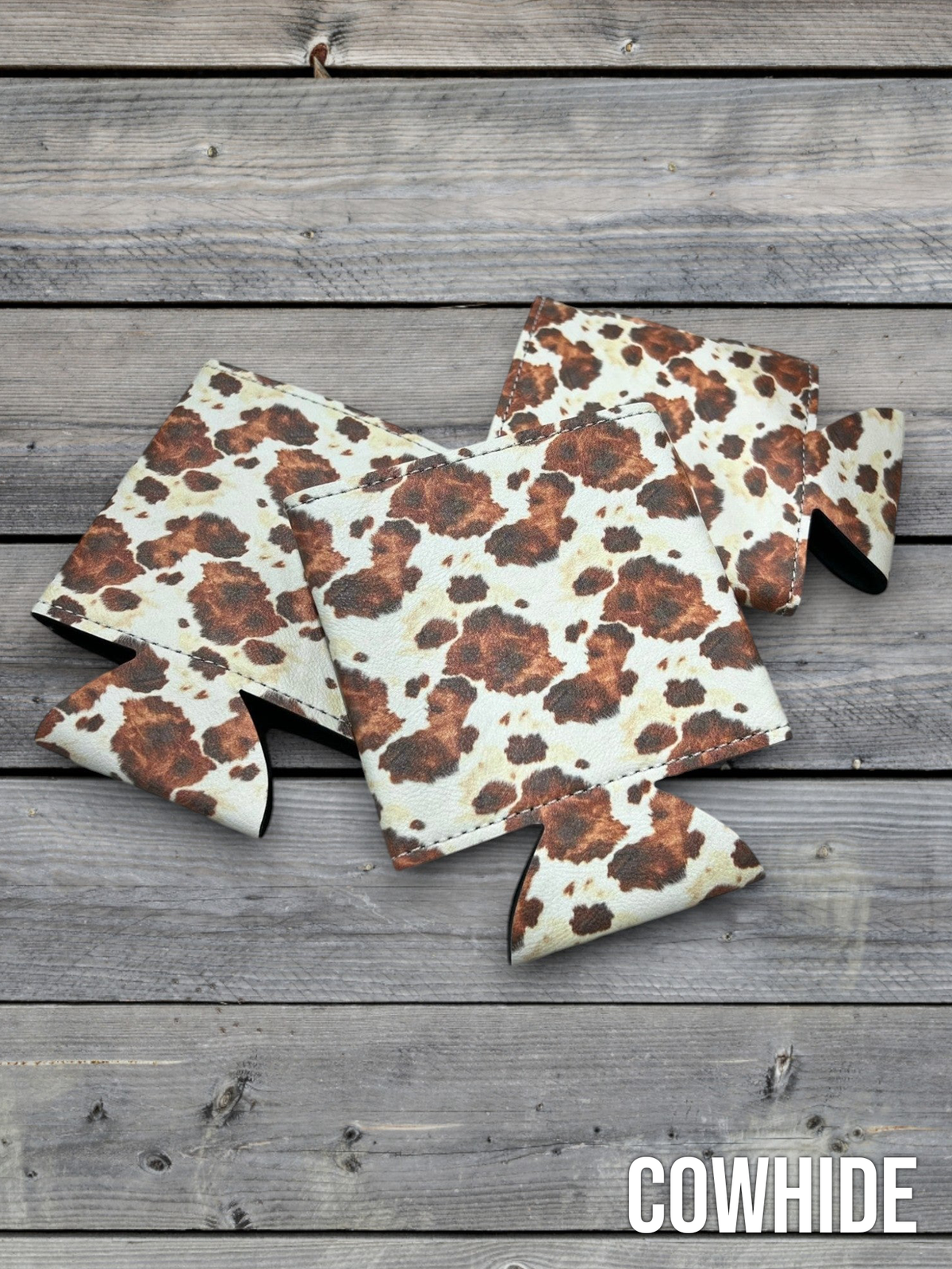 Cowhide print Premium Leatherette can coolers in a black and white hide pattern, laid flat and collapsed.