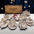 Two engraved wooden gift box lids with the six carol ornaments arranged around them on a dark background