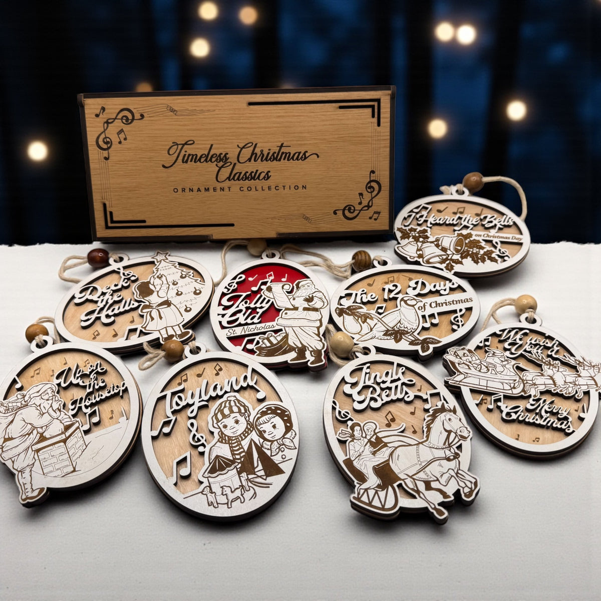 Two engraved wooden gift box lids with the six carol ornaments arranged around them on a dark background