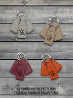 Four Premium Leatherette keychains in cream, tan, maroon and orange on weathered wood, each laser engraved with a sample design.