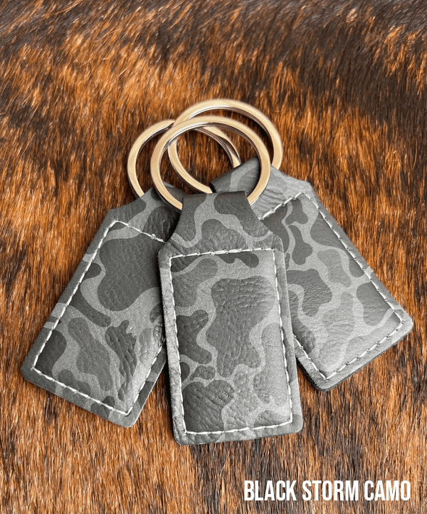 Three Black Storm Camo Premium Leatherette keychains in a grey camouflage pattern, fanned out on a split ring.