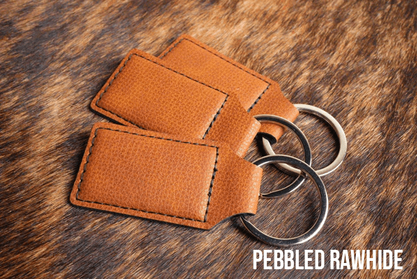 Three Pebbled Rawhide Premium Leatherette keychains with a textured tan grain, fanned out on a split ring.