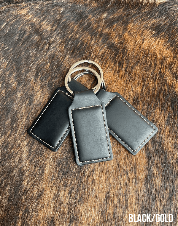 Three black Premium Leatherette keychains that engrave to gold, fanned out on a split ring.